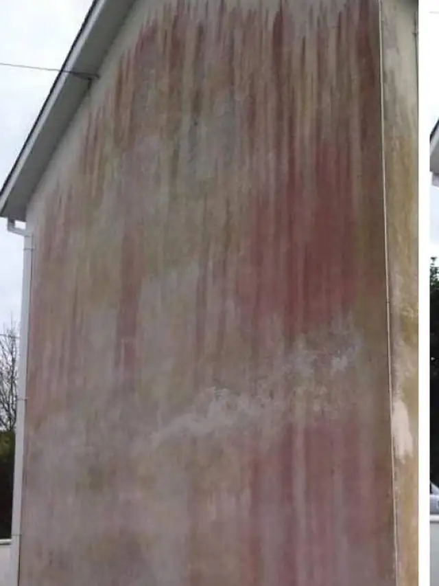 A stained rendered gable wall before cleaning
